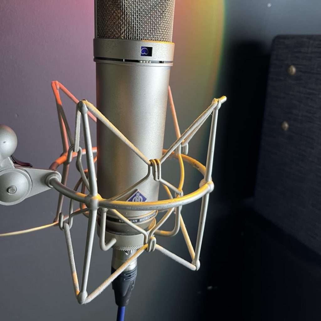 Close-up of a neumann microphone in a shock mount, set against a backdrop with soft lighting, ready for vocal recording in a studio.